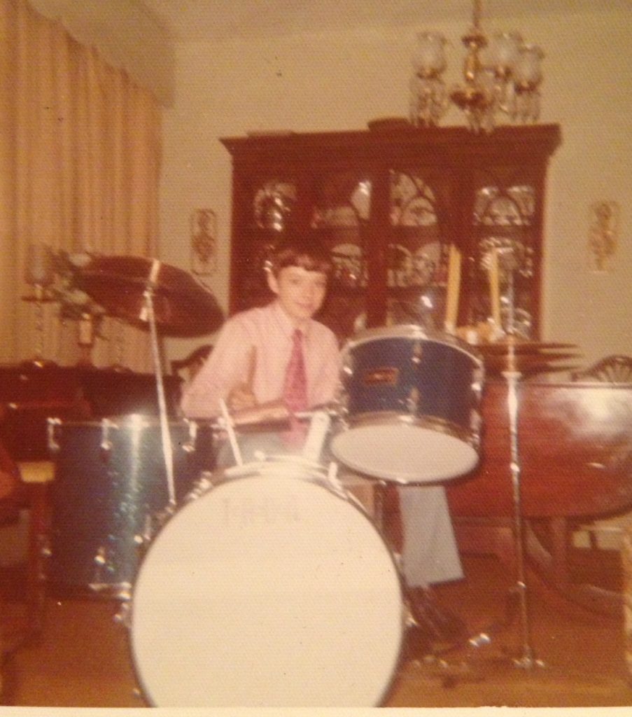 John Wittmann with a blue sparkle drum kit as a child