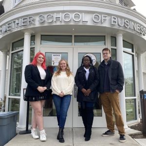 Four college students standing in front of the School of Business