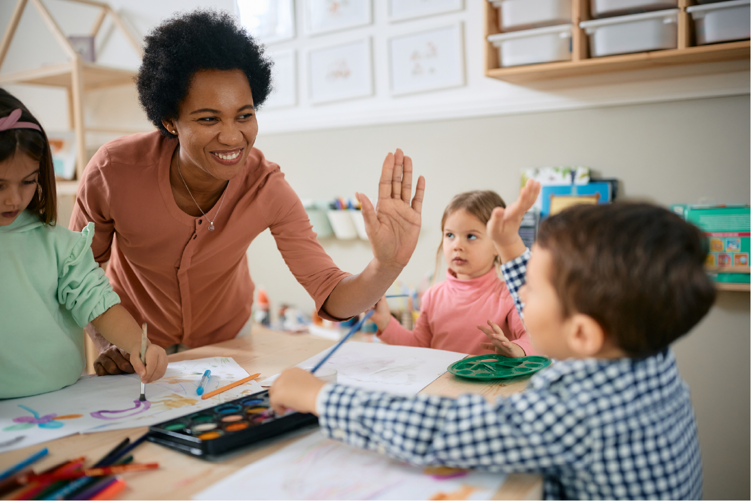 Early childhood teacher giving student high five