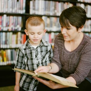 elementary school teacher reading to a student in a library after deciding if teaching was right for her