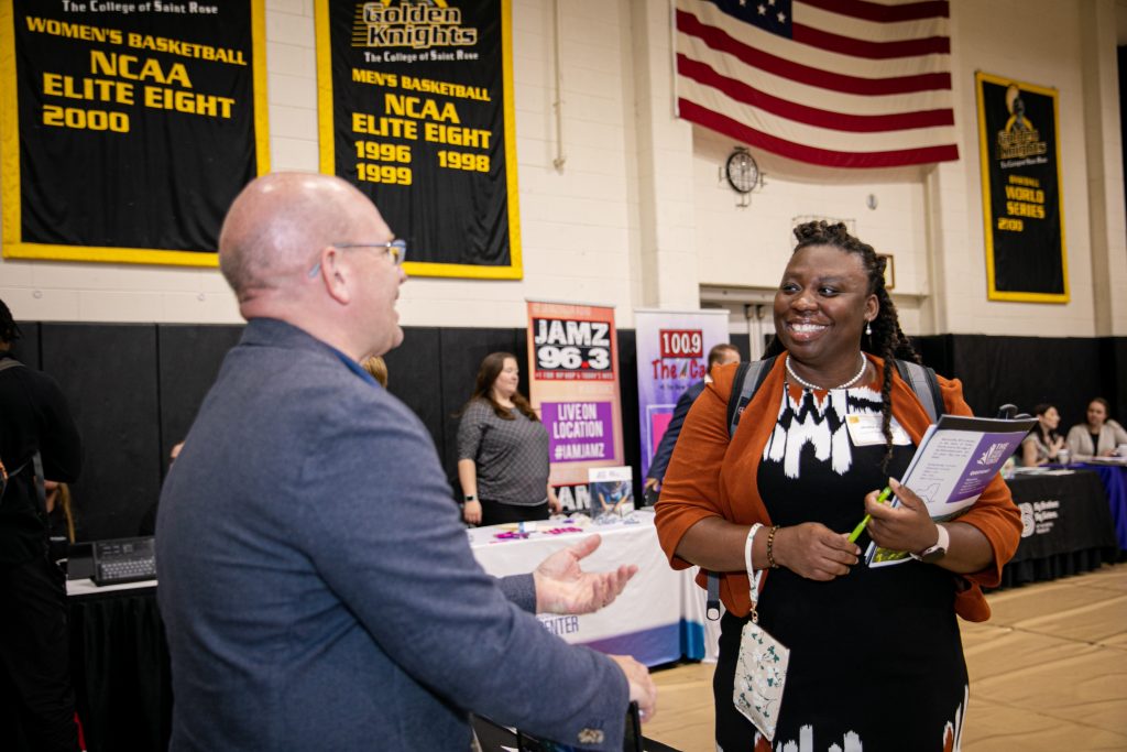 Professional woman speaking to a man at a career fair.