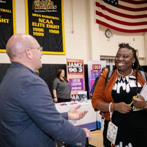 Professional woman speaking to a man at a career fair.